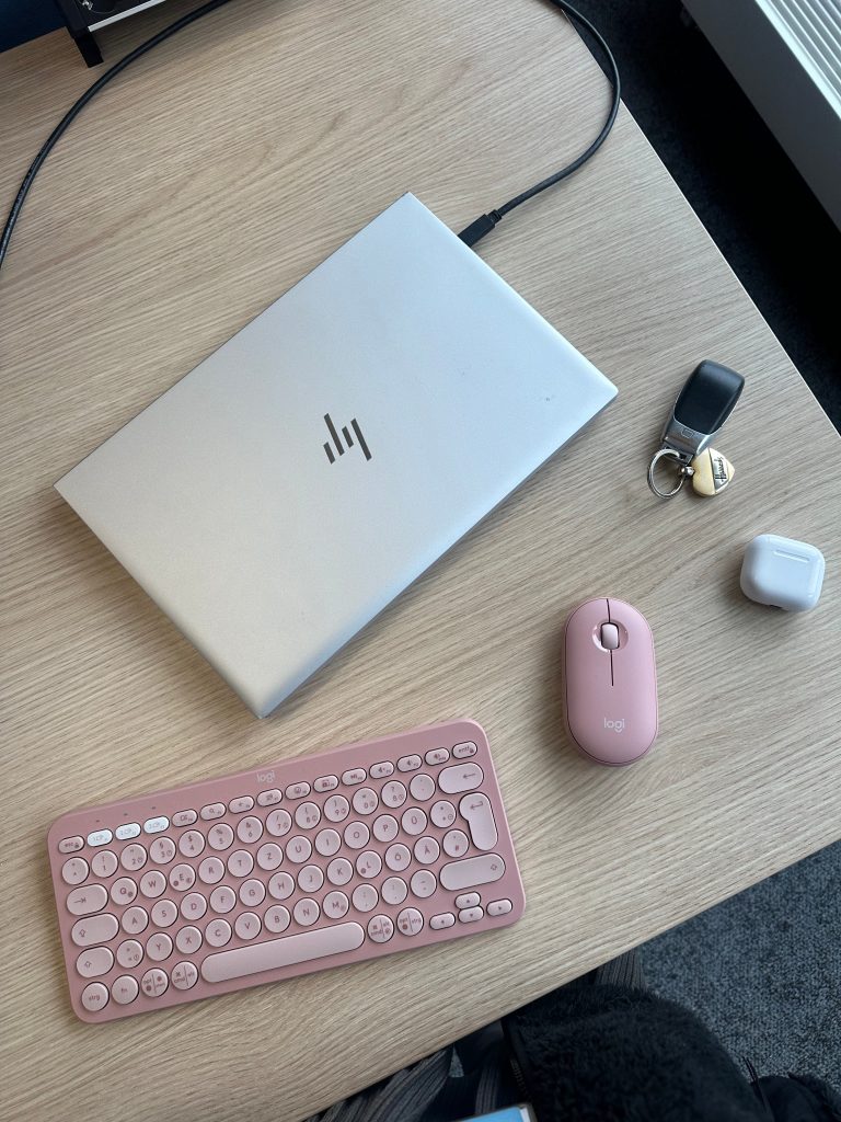 Minimal workspace with laptop and soft colours, reflecting intentional work and a calm daily routine.